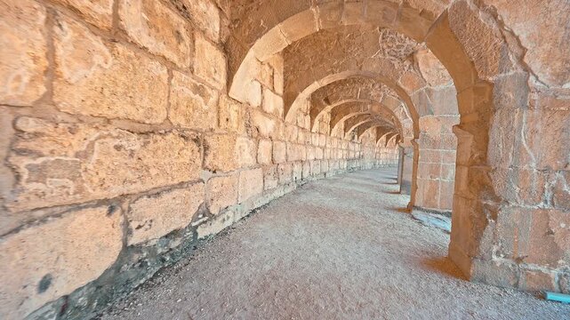 Aspendos Ancient City in Antalya, Turkiye, features a visitor walking among ancient stone columns, revealing its timeless Roman heritage.