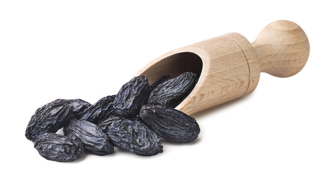 Raisins spilled from a wooden scoop on a white. Isolated