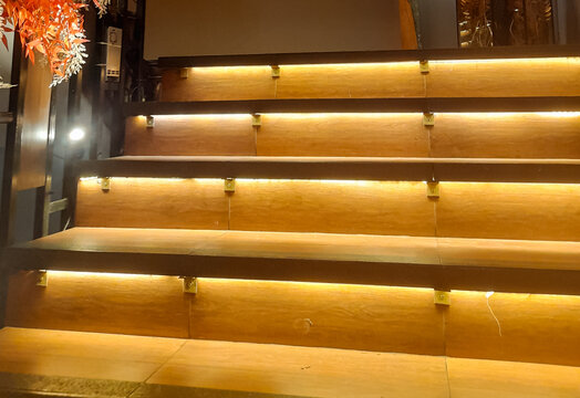 Modern wooden staircase with warm hidden LED strip lighting in a cozy interior design.