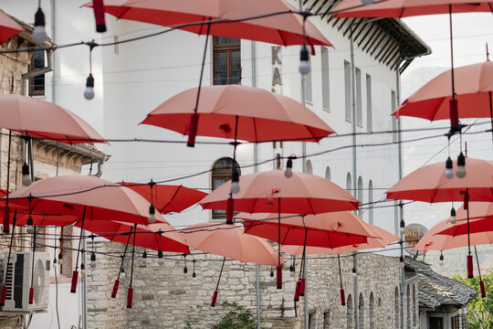 ed umbrellas and light bulbs hanging over a street in Gjirokaster, Albania