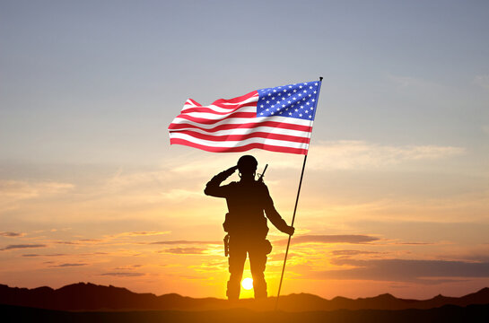 Silhouettes of a soldier with USA flag against the sunset. Veterans Day, Memorial Day concept