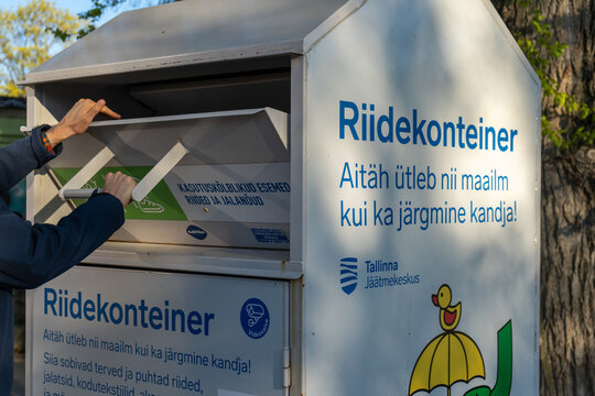 Man donating used clothes to charity collection container in Tallinn Estonia