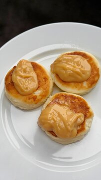 Syrniki, cottage cheese pancakes with condenced milk. delicious ukrainian dessert on white plate closeup, perfect minimal breakfast