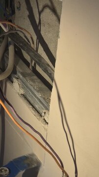 Construction worker cutting drywall with an oscillating multi-tool during a home renovation. High-angle close-up shot focused on the blade action.