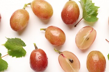 Fototapeta premium Fresh ripe grapes and green leaves on white background, flat lay