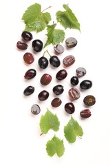 Fototapeta premium Fresh ripe grapes and green leaves on white background, flat lay
