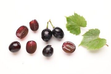 Fototapeta premium Fresh ripe grapes and green leaves on white background, flat lay