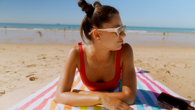 Woman in sunglasses looking sideways while resting at the beach