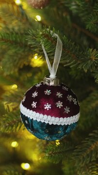 Vertical video. Woman decorating Christmas tree with Christmas ball.