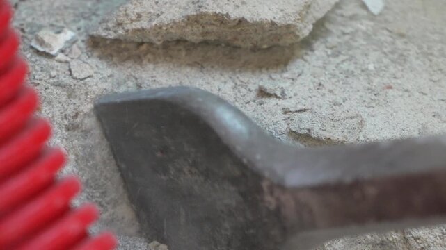 Concrete demolition tool shattering stone floor next to vibrant protective conduit. Macro shot.