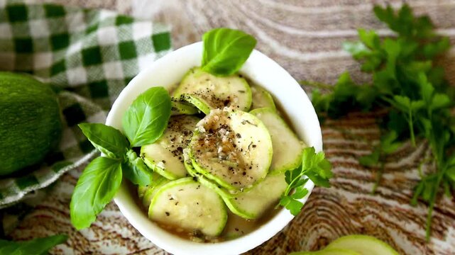Fresh zucchini appetizer with garlic herbs on light wood background