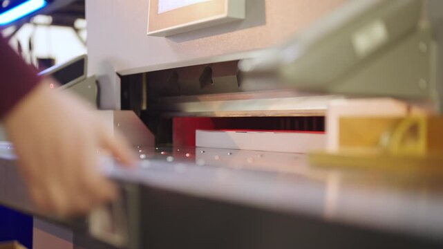 Person prepare to cut printed pages into smaller pieces at manufacturing press