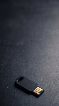 USB flash drive on dark textured surface. Portable data storage for cybersecurity and secure file transfer. Digital information security and corporate technology concept.