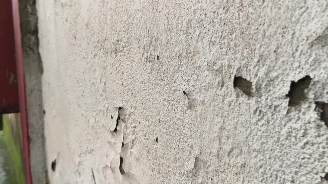 Damaged plaster wall with cracks and peeling paint. Close-up of a severely damaged, aged plaster wall. Heavy cracks and large areas of peeling and spalling paint layers are prominent across.