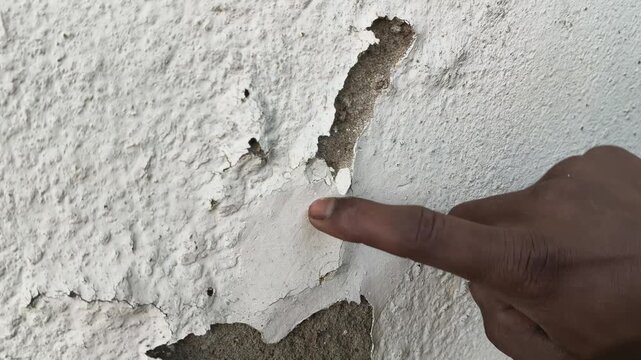 Damaged plaster wall with cracks and peeling paint. Close-up of a severely damaged, aged plaster wall. Heavy cracks and large areas of peeling and spalling paint layers are prominent across.