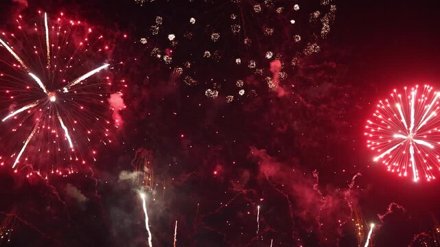 Vibrant red fireworks explode across the dark night sky with smoky textures, creating a festive background for Chinese New Year celebrations, Christmas, holiday events, and grand festivals