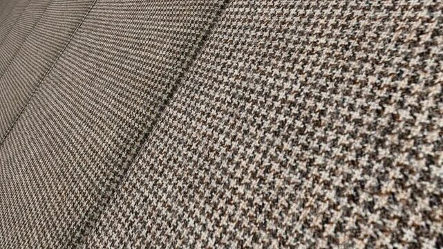 Artistic Cinematic Movement Along Italian Brown Houndstooth Wool Fabric with Angled Camera Perspective, Warm Lighting and Distinctive Woven Patterns