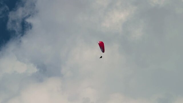 paraglider soaring high in the deep cloud sky above majestic white clouds. Perfect for travel, freedom, adventure, and extreme outdoor sports concepts..