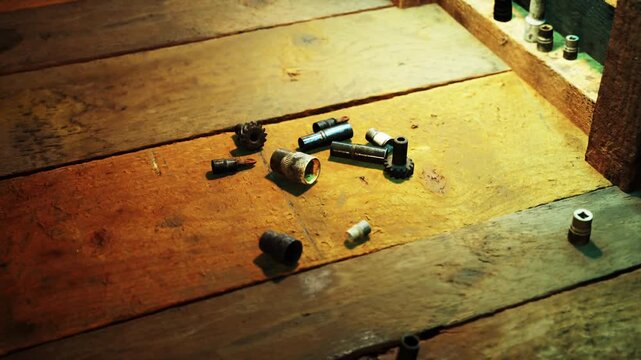 Scattered mechanical parts rest on a distressed wooden floor. Warm light highlights their various shapes, creating intriguing shadows and textures in the surroundings.