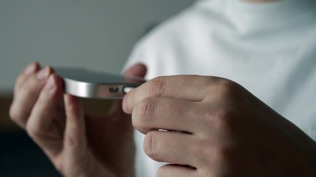 A man in a bright room connects a mobile phone to a charger.