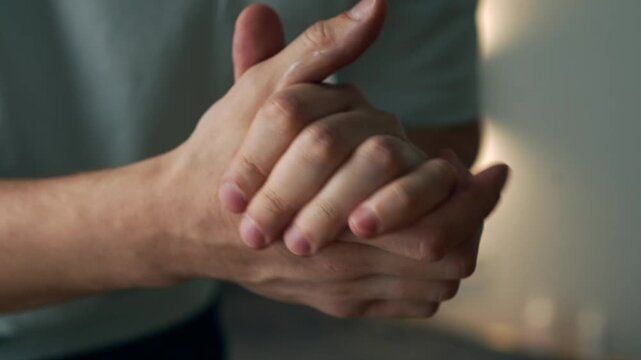 Young Man Rubbing Moisturizing Cream into His Hands to Prevent Dry Skin