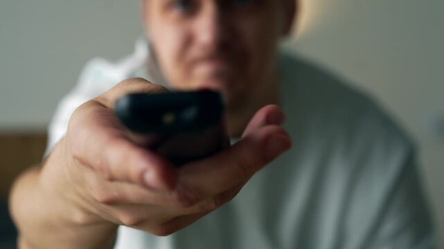 Annoyed Man Pressing Buttons on TV Remote Due to Technical Problems