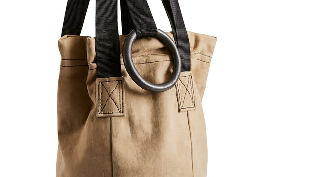 Isolated sturdy beige canvas tote bag with black webbing straps and large metal ring