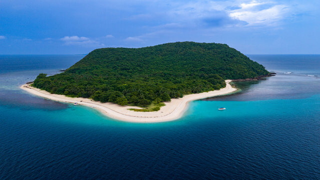 Aerial view of a lush tropical island with a white sand beach surrounded by turquoise and deep blue waters in Busuanga, Mimaropa, Philippines.