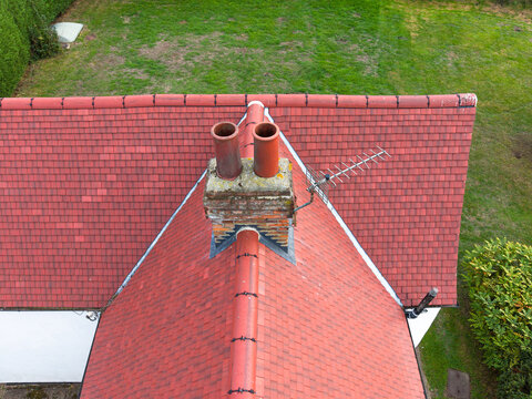 Drone inspection view of a newly installed terracotta-coloured roof on an old English cottage. Note the brick-built chimney stack which also needs renovating.
