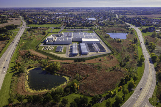 Aerial view of a large data center facility surrounded by autumn foliage, ponds, and nearby roads in Volo, Illinois, United States.