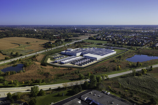Aerial view of a data center complex surrounded by autumn fields, roads, and a small pond in Volo, Illinois, United States.