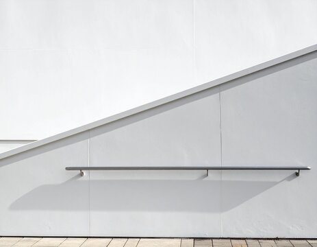 Horizontal stainless steel handrail on a plain white wall with large blank space for text