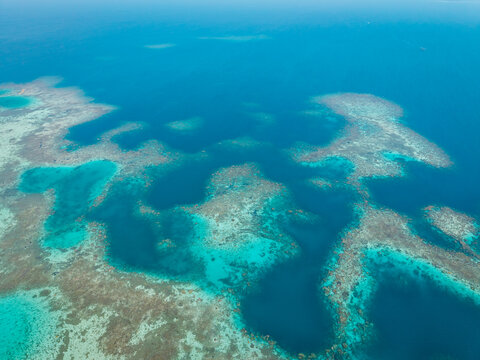 Aerial view of the vibrant coral reef with turquoise shallow waters and deep blue sea channels in Karimunjawa, Central Java, Indonesia.