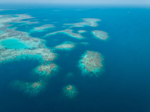 Aerial view of vibrant coral reef formations surrounded by deep blue ocean waters in Karimunjawa, Central Java, Indonesia.
