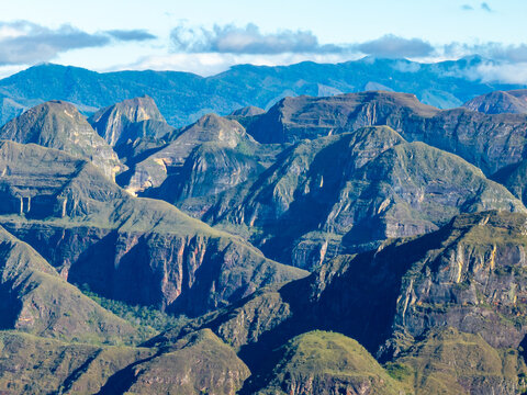 Aerial view of Codo de los Andes featuring rugged mountain peaks, rocky slopes, and deep shadows under a clear sky in Samaipata, Santa Cruz Department, Bolivia.