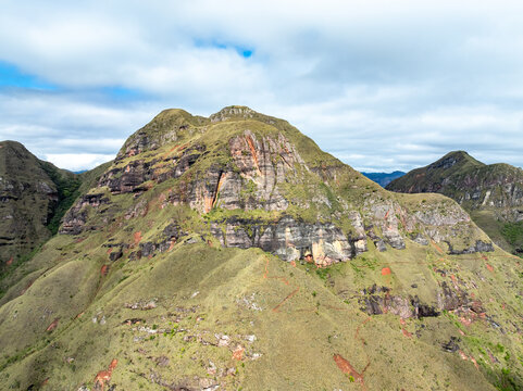 Aerial view of Codo de los Andes featuring rugged rocky cliffs, grassy slopes, and dramatic geological formations under a cloudy sky, Samaipata, Santa Cruz Department, Bolivia.
