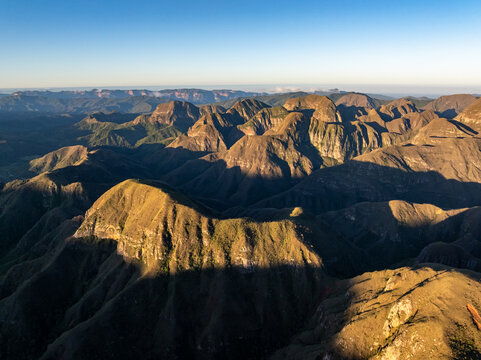 Aerial view of Codo de los Andes featuring rugged mountain peaks illuminated by golden hour light with deep shadows and vast terrain in Samaipata, Santa Cruz Department, Bolivia.