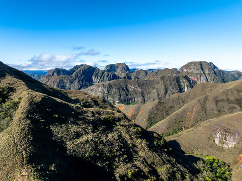 Aerial view of Codo de los Andes featuring rugged mountain ridges, rocky slopes, and lush green vegetation under a clear blue sky in Samaipata, Santa Cruz Department, Bolivia.