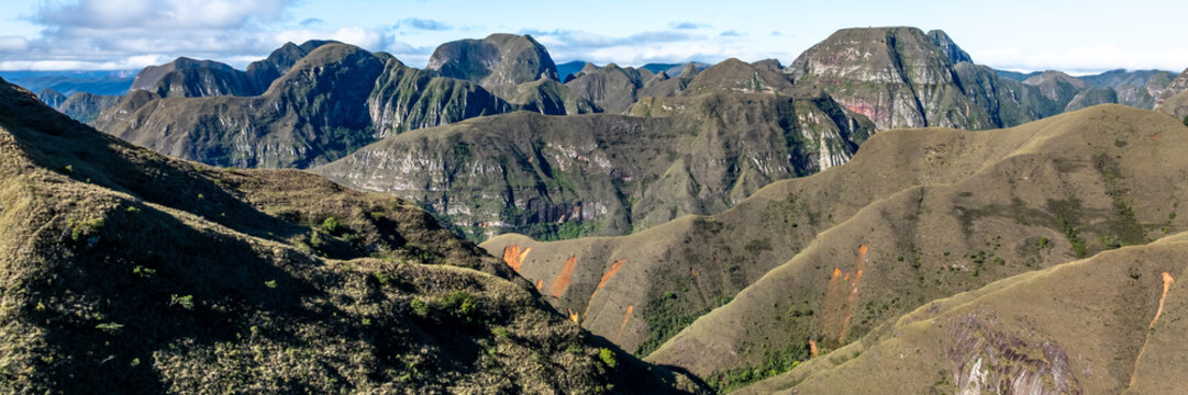 Aerial view of Codo de los Andes featuring rugged mountain ridges, grassy slopes, and deep valleys under a bright sky in Samaipata, Santa Cruz Department, Bolivia.