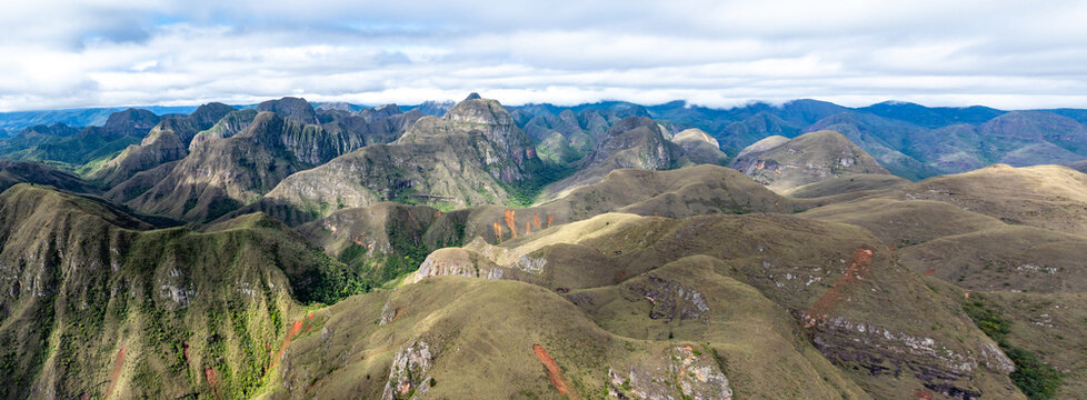 Aerial view of the Codo de los Andes mountain range with rolling hills, rocky outcrops, and lush green vegetation under a cloudy sky in Samaipata, Santa Cruz Department, Bolivia.