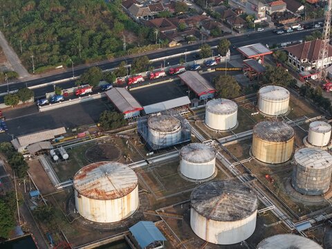 Aerial view of PT Pertamina Terminal BBM Sanggaran featuring large industrial storage tanks, pipelines, and fuel tanker trucks parked near a road in Kecamatan Denpasar Selatan, Bali, Indonesia.