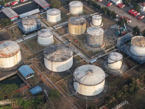 Aerial view of PT Pertamina Terminal BBM Sanggaran featuring large cylindrical fuel storage tanks, complex piping networks, and service vehicles in Kecamatan Denpasar Selatan, Bali, Indonesia.
