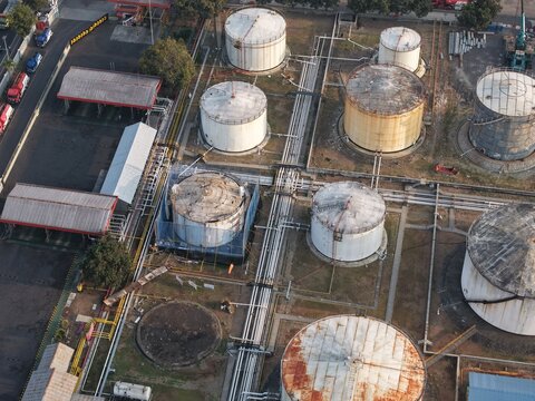 Aerial view of PT Pertamina Persero Terminal BBM Sanggaran with large industrial oil storage tanks and interconnected piping systems in Kecamatan Denpasar Selatan, Bali, Indonesia.