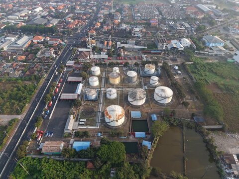 Aerial view of PT Pertamina Terminal BBM Sanggaran featuring large fuel storage tanks within an industrial facility near urban roads in Kecamatan Denpasar Selatan, Bali, Indonesia.