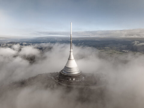 Aerial view of Jested Tower rising above a sea of clouds on the summit of Jested mountain in Liberec, Liberecky kraj, Czechia.