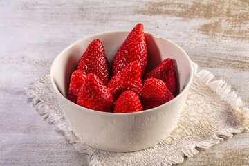 Fresh red strawberries in a simple white ceramic bowl on a rustic wooden table © Andrei Starostin
