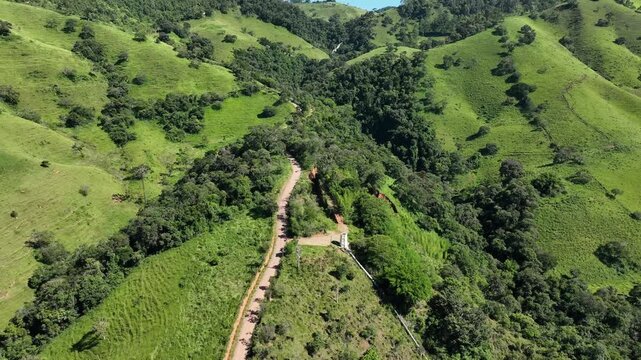 Vista a&eacute;rea de estrada estreita entre morros arborizados