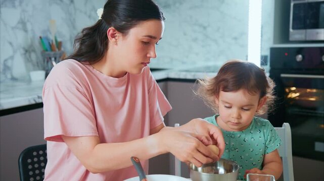 Mother and child prepare cake together in cozy kitchen. Child watches closely, eager to help. Mother guides gently, smiles warmly. Ideal for family, parenting, or cooking themes