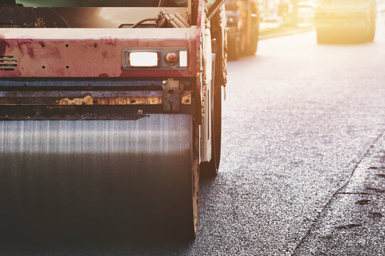 A large industrial road roller compacts newly laid asphalt on a city street. This urban construction activity is vital for modern infrastructure development in the metropolis.