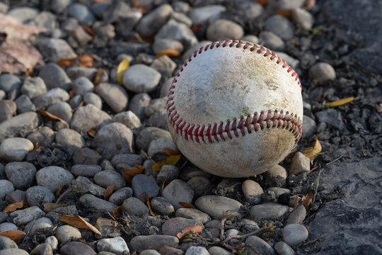 Weathered Baseball Abandoned on Rocky Ground Outdoors